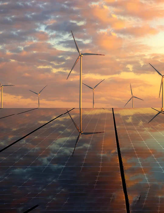 A sunset and wind turbines reflected on the surface of solar panels 